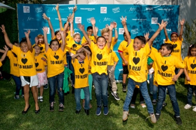 Children jumping with their hands in the air wearing I heart to read t-shirts