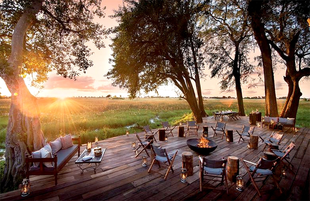 Deck overlooking grassland at a safari camp with seats and a fire pit