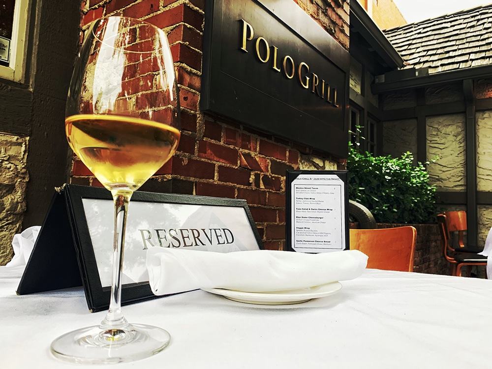 Polo Grill sign with a glass of white wine on a white tablecloth and a reserved sign