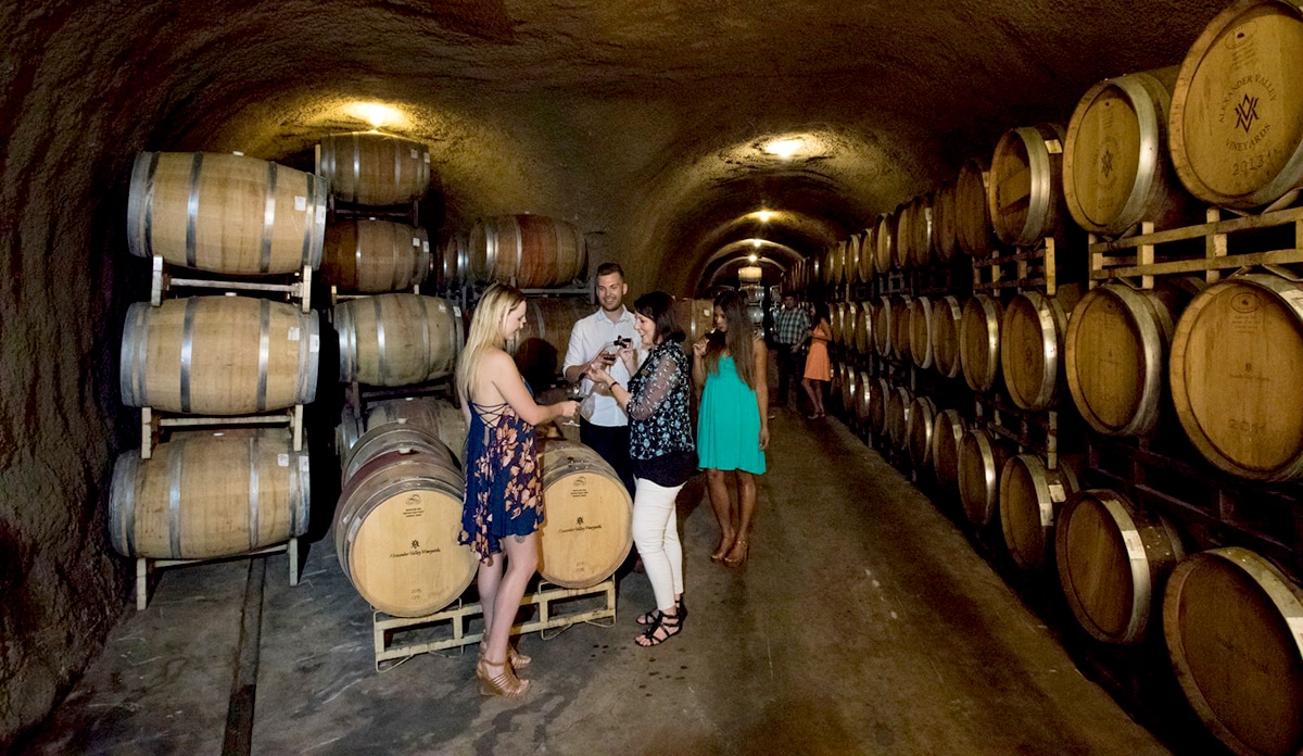 People tasting wine from a barrel in a cellar