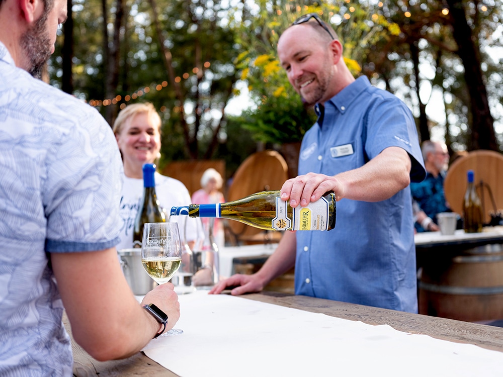 Rombauer white wine being poured by a man behind a bar - lot for SCWA